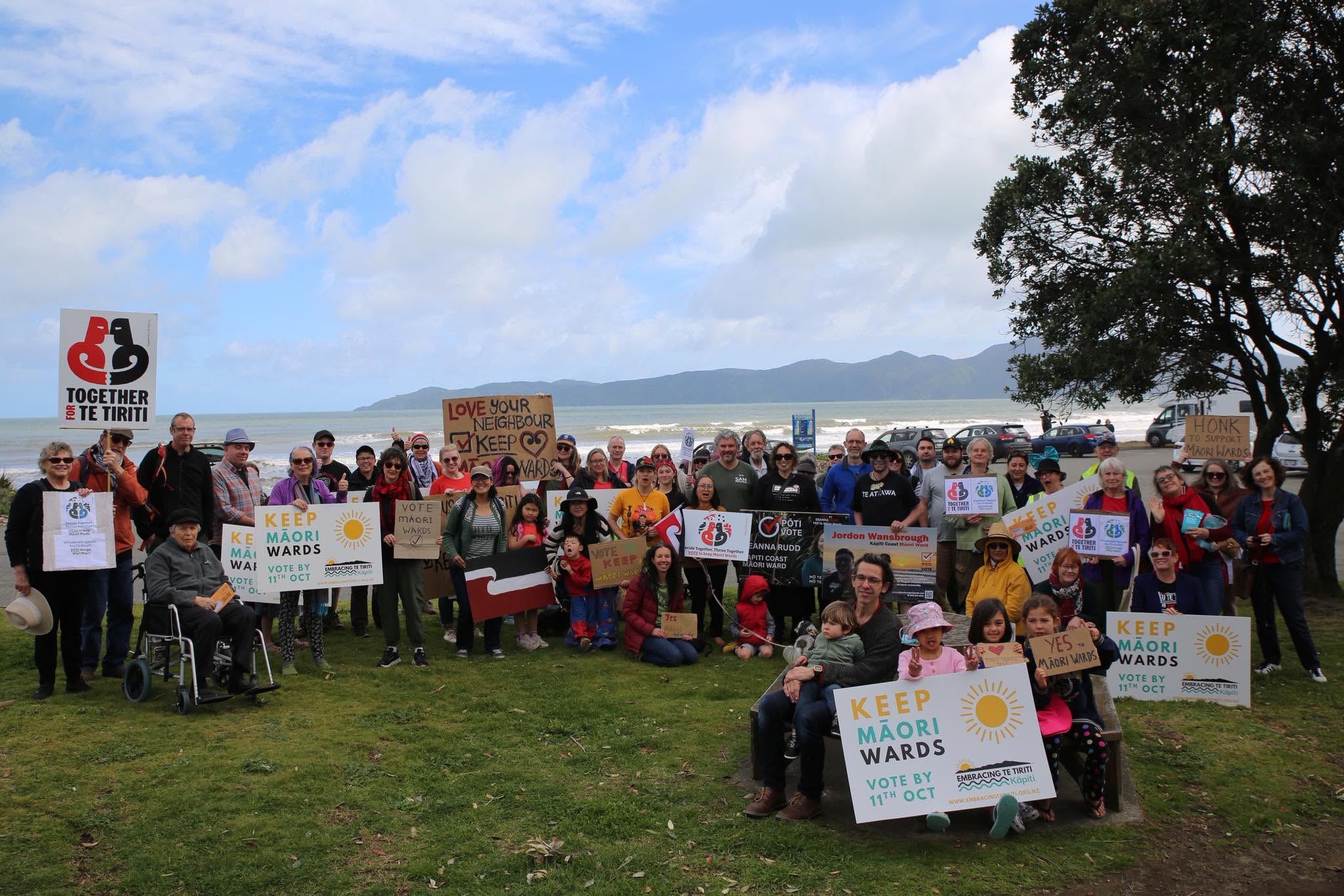 Group of people outdoors holding signs advocating for Māori wards and Te Tiriti rights